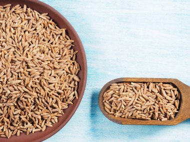 Kimyon tohumları (Cuminum), kil tabakta Jeera ve mavi tabakta kepçe