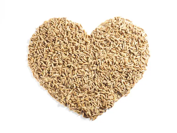 Cumin seeds (Cuminum), Jeera in the shape of a heart on a white Royalty Free Stock Images