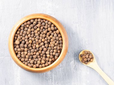 Allspice (Jamaika biberi) tahta bir kap ve gri bir ba üzerinde kaşık