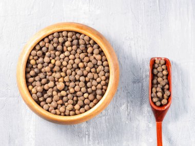 Allspice (Jamaika biberi) ahşap bardakta ve gri sırtında kepçe