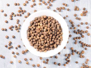 Allspice (Jamaika biberi) gri arka planda beyaz bir fincanda 