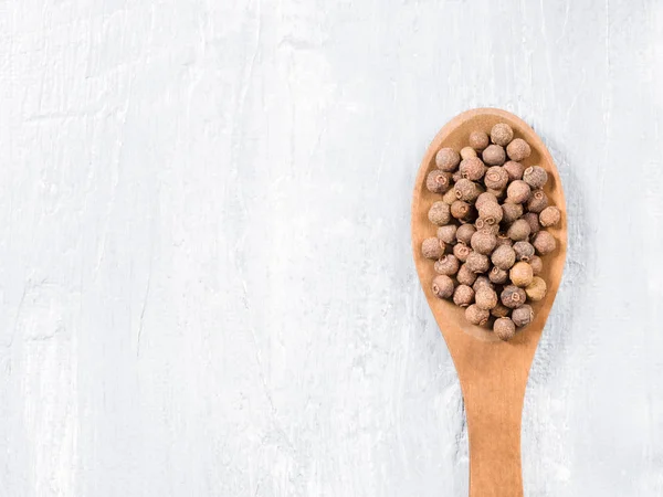 Allspice (Jamaica pepper) på en träsked på en grå bakgrund — Stockfoto