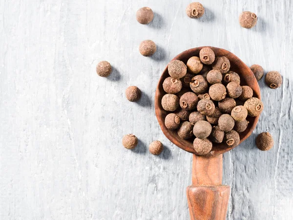 Piment (Jamaica-Pfeffer) auf einem Holzlöffel auf grauem Hintergrund — Stockfoto