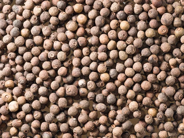 Allspice (Jamaica peper) op een bruine houten ondergrond — Stockfoto