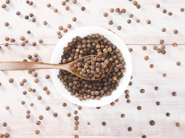 Piment (Jamaica-Pfeffer) in einer weißen Tasse und einem Löffel auf einem braunen — Stockfoto