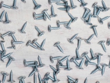 Açık kahverengi arka planda gümüş renkli çelik vidalar. İndu