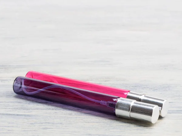 Flacon vaporisateur cosmétique rose et bleu horizontalement sur fond en bois — Photo