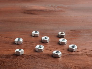 Kahverengi ahşap arka planda gümüş rengi çelik fındıklar.