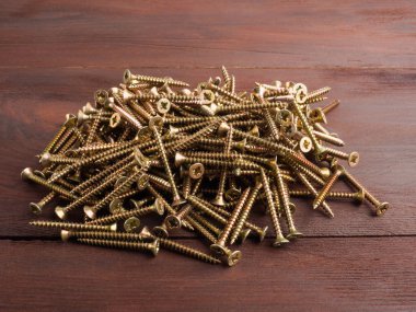 Kahverengi arka planda bir grup çelik vida. Sanayi teması