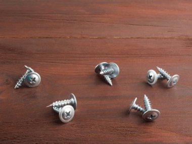 Kahverengi ahşap arka planda gümüş renkli metal vidalar. Ben...