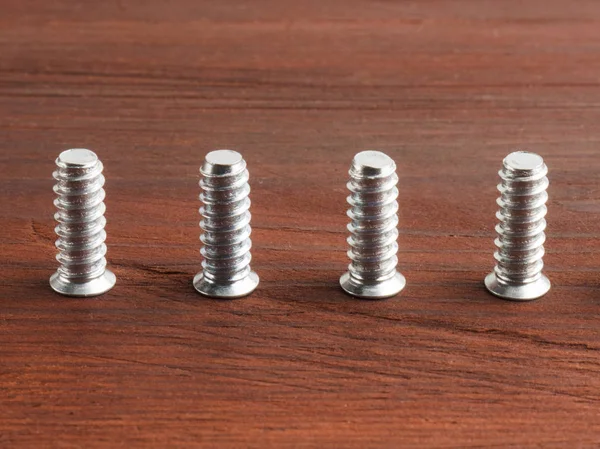 Set de cuatro tornillos de acero color plata sobre fondo de madera marrón —  Fotos de Stock