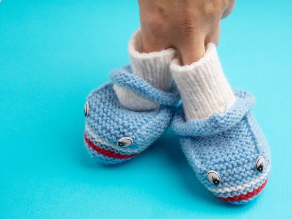 Chaussures Tricotées Bleu Bébé Avec Main Des Femmes Sur Fond — Photo