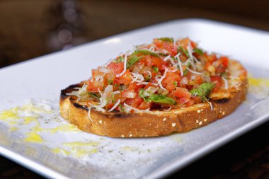 Peynirli ve sarımsaklı kızarmış ekmeğe domatesli, otlu ve yağlı