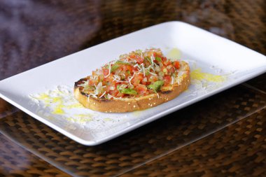 Peynirli ve sarımsaklı kızarmış ekmeğe domatesli, otlu ve yağlı.