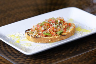 Peynirli ve sarımsaklı kızarmış ekmeğe domatesli, otlu ve yağlı.