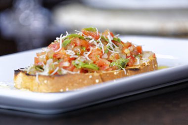 Peynirli ve sarımsaklı kızarmış ekmeğe domatesli, otlu ve yağlı.