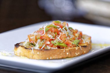 Peynirli ve sarımsaklı kızarmış ekmeğe domatesli, otlu ve yağlı.