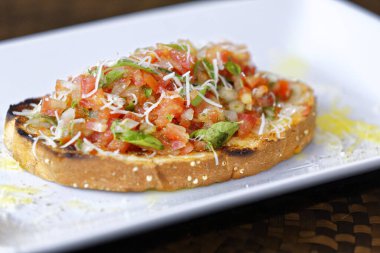 Peynirli ve sarımsaklı kızarmış ekmeğe domatesli, otlu ve yağlı.