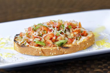 Peynirli ve sarımsaklı kızarmış ekmeğe domatesli, otlu ve yağlı.