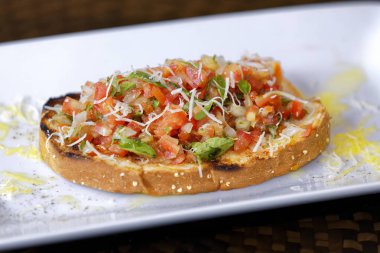 Peynirli ve sarımsaklı kızarmış ekmeğe domatesli, otlu ve yağlı.