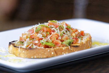 Peynirli ve sarımsaklı kızarmış ekmeğe domatesli, otlu ve yağlı.