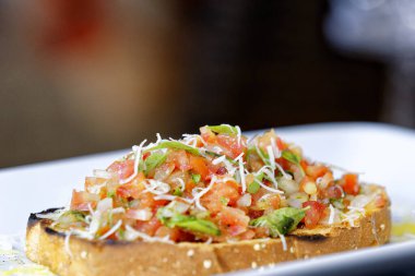 Peynirli ve sarımsaklı kızarmış ekmeğe domatesli, otlu ve yağlı.