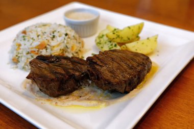 Peynir soslu fileto, bitkilerle birlikte pirinç, kabak çekirdeği ve patates sotesi.