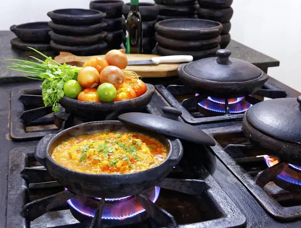 Moqueca Capixaba on fire in clay pot with various ingredients in the background, state of Esprito Santo, Brazil — Stock Image Moqueca Capixaba Fire Clay Pot Various Ingredients Background State Esprito Stock Picture