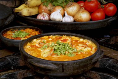 Lezzetli Moqueca capixaba ve kil kaplarda sebzeler