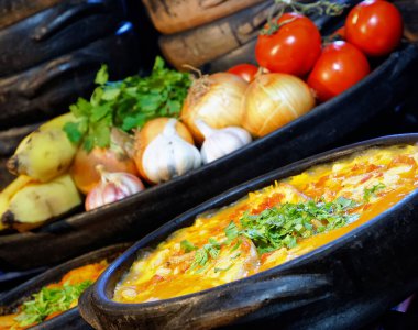 Lezzetli Moqueca capixaba ve kil kaplarda sebzeler