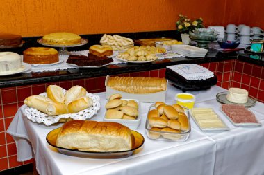 Çeşitli lezzetli ekmekler, kekler, peynirli ekmek ve simit içeren kahvaltı masası..