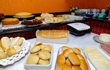 Çeşitli lezzetli ekmekler, kekler, peynirli ekmek ve simit içeren kahvaltı masası..