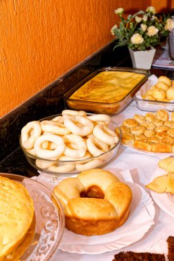 Çeşitli ekmekler, kekler, peynirli ekmek ve simit içeren kahvaltı masası..