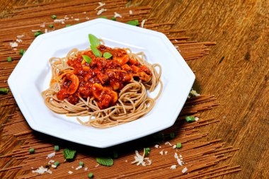 Domuz pastırmalı ve şampiyon soslu tam tahıllı spagetti fesleğenle süslenmiş ve yanında patates ekmeği ve vişneli domates..