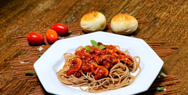 Domuz pastırmalı ve şampiyon soslu tam tahıllı spagetti fesleğenle süslenmiş ve yanında patates ekmeği ve vişneli domates..