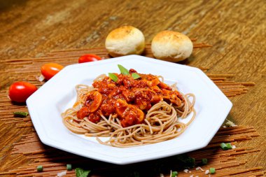 Domuz pastırmalı ve şampiyon soslu tam tahıllı spagetti fesleğenle süslenmiş ve yanında patates ekmeği ve vişneli domates..