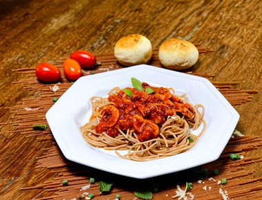 Domuz pastırmalı ve şampiyon soslu tam tahıllı spagetti fesleğenle süslenmiş ve yanında patates ekmeği ve vişneli domates..