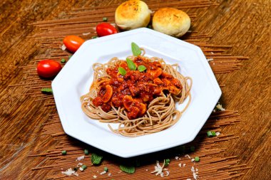 Domuz pastırmalı ve şampiyon soslu tam tahıllı spagetti fesleğenle süslenmiş ve yanında patates ekmeği ve vişneli domates..