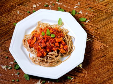 Domuz pastırmalı ve şampiyon soslu tam tahıllı spagetti fesleğenle süslenmiş ve yanında patates ekmeği ve vişneli domates..