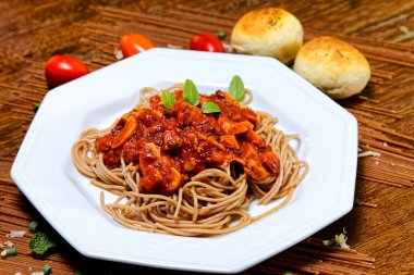 Domuz pastırmalı ve şampiyon soslu tam tahıllı spagetti fesleğenle süslenmiş ve yanında patates ekmeği ve vişneli domates..