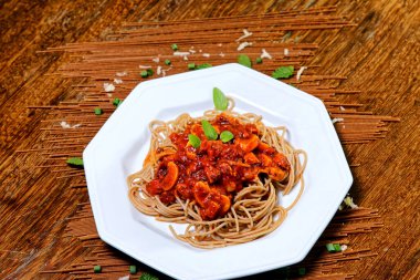 Domuz pastırmalı ve şampiyon soslu tam tahıllı spagetti fesleğenle süslenmiş ve yanında patates ekmeği ve vişneli domates..