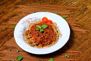 Bolonez soslu Fettuccine, fesleğen ve kiraz domatesleriyle süslenmiş, yanında kekik ekmeği..