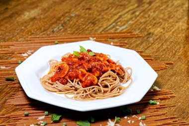 Domuz pastırmalı ve şampiyon soslu tam tahıllı spagetti fesleğenle süslenmiş ve yanında patates ekmeği ve vişneli domates..