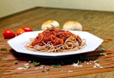 Domuz pastırmalı ve şampiyon soslu tam tahıllı spagetti fesleğenle süslenmiş ve yanında patates ekmeği ve vişneli domates..