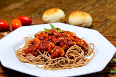 Domuz pastırmalı ve şampiyon soslu tam tahıllı spagetti fesleğenle süslenmiş ve yanında patates ekmeği ve vişneli domates..