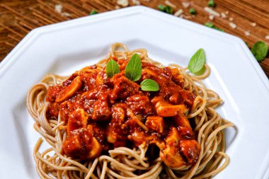 Domuz pastırmalı ve şampiyon soslu tam tahıllı spagetti fesleğenle süslenmiş ve yanında patates ekmeği ve vişneli domates..