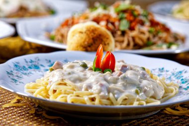 Bezelye ve jambonlu, beyaz soslu tam tahıllı spagetti.