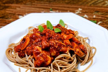 Domuz pastırmalı ve şampiyon soslu tam tahıllı spagetti fesleğenle süslenmiş ve yanında patates ekmeği ve vişneli domates..