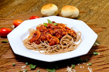Domuz pastırmalı ve şampiyon soslu tam tahıllı spagetti fesleğenle süslenmiş ve yanında patates ekmeği ve vişneli domates..