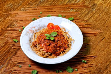 Bolonez soslu Fettuccine, fesleğen ve kiraz domatesleriyle süslenmiş, yanında kekik ekmeği..